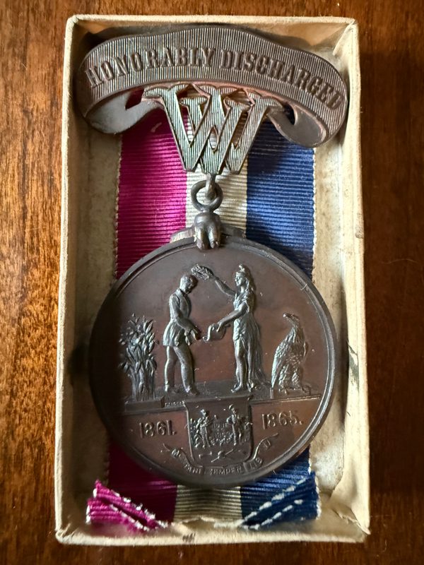West Virginia medal showing a soldier crowned by a female figure, the dates 1861 and 1865, and an Honorably Discharged clasp